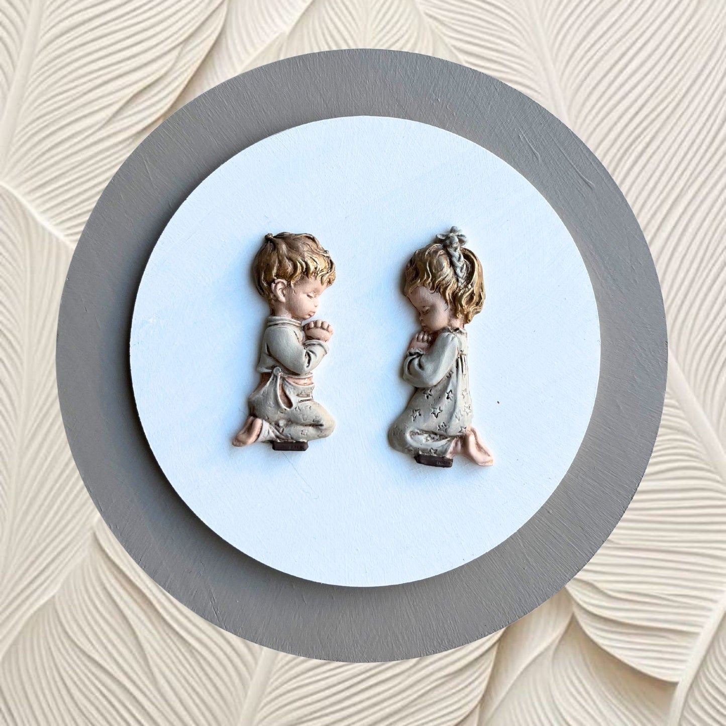 Large grey painting of a girl and boy praying